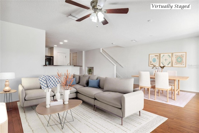 living room with a textured ceiling, light hardwood / wood-style floors, and ceiling fan