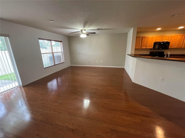 unfurnished living room featuring a textured ceiling, ceiling fan, sink, and dark hardwood / wood-style floors