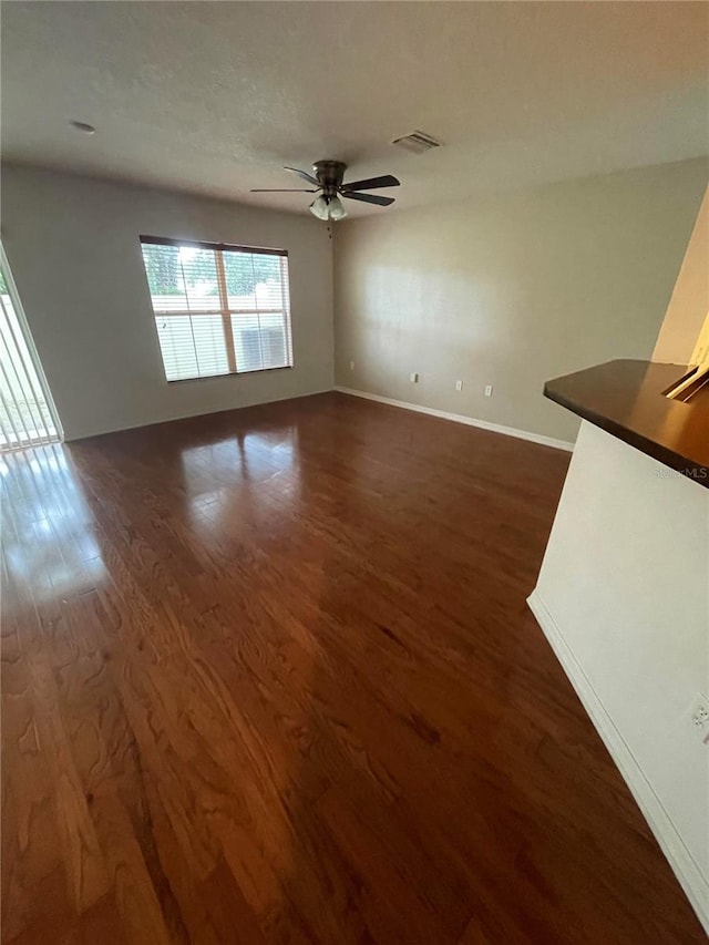 unfurnished living room featuring ceiling fan and dark hardwood / wood-style flooring