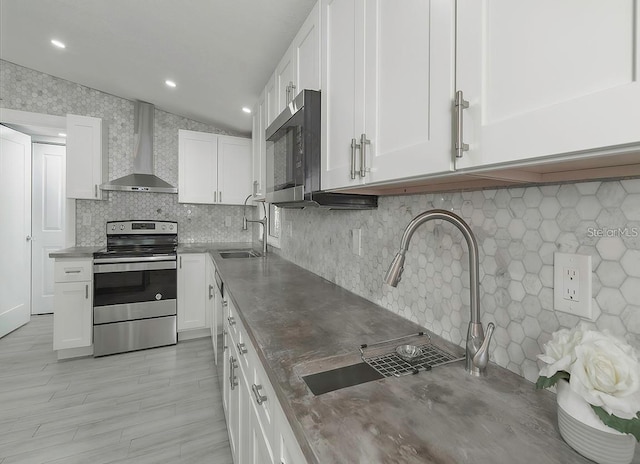 1428 Illinois Ave, Palm Harbor, FL 34683 - kitchen featuring stainless steel appliances, wall chimney range hood, a sink, white cabinets, and decorative backsplash