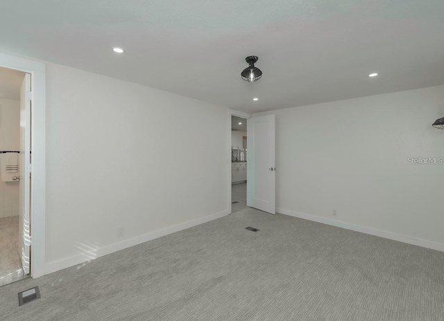 unfurnished bedroom with ensuite bathroom and light colored carpet