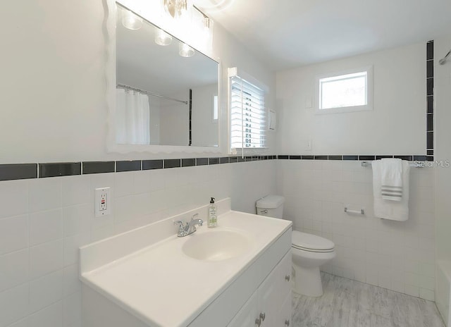 bathroom with vanity, tile walls, and toilet