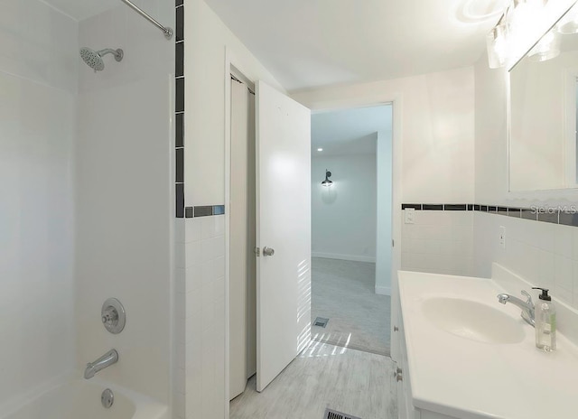 bathroom with vanity, shower / bathing tub combination, wood-type flooring, and tile walls