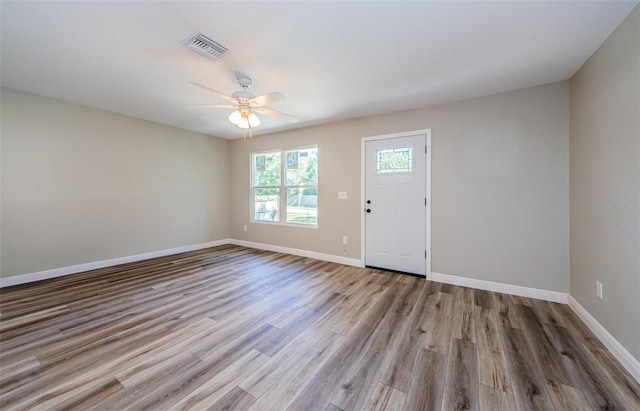 entryway featuring a ceiling fan, wood finished floors, visible vents, and baseboards