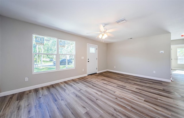 spare room featuring visible vents, ceiling fan, baseboards, and wood finished floors