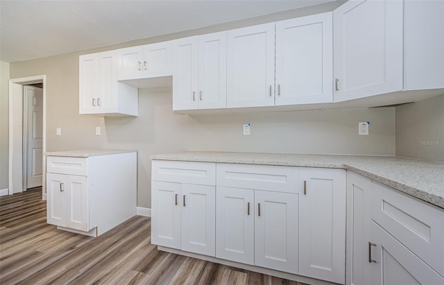 kitchen featuring baseboards, light wood finished floors, and white cabinets