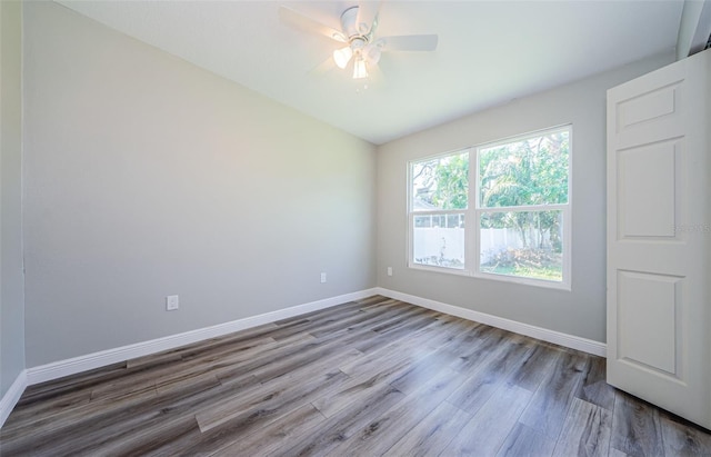 spare room featuring lofted ceiling, a ceiling fan, baseboards, and wood finished floors