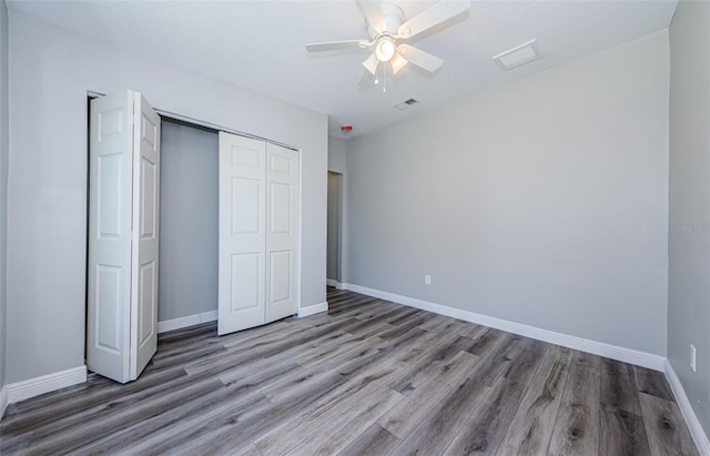 unfurnished bedroom with a closet, visible vents, baseboards, and wood finished floors