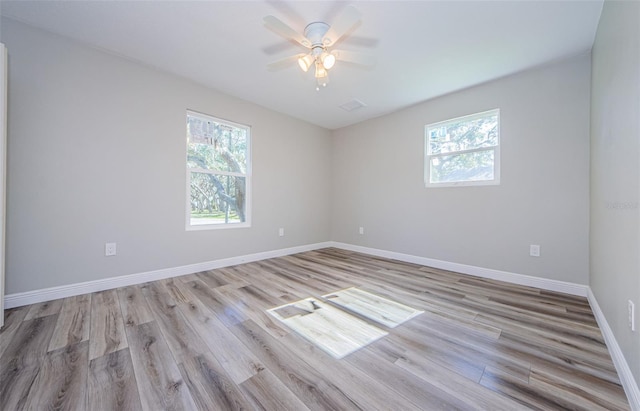 unfurnished room with light wood-style flooring, a wealth of natural light, and baseboards