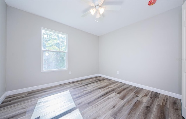 empty room with ceiling fan, wood finished floors, and baseboards