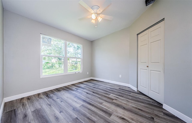 unfurnished bedroom featuring a closet, dark wood-type flooring, vaulted ceiling, ceiling fan, and baseboards