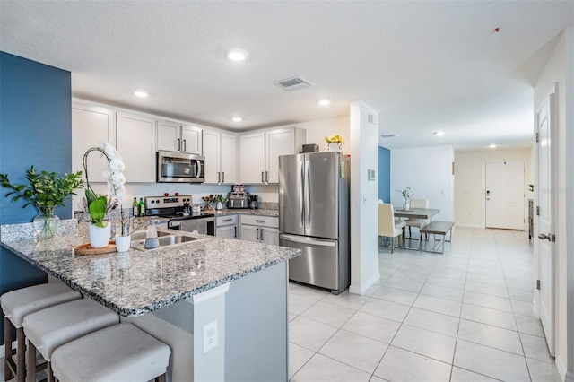 kitchen featuring kitchen peninsula, stainless steel appliances, white cabinets, and dark stone countertops