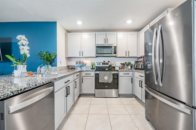 kitchen featuring light stone countertops, sink, light tile patterned floors, white cabinets, and appliances with stainless steel finishes