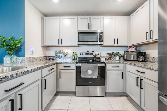 kitchen with a textured ceiling, white cabinetry, and stainless steel appliances