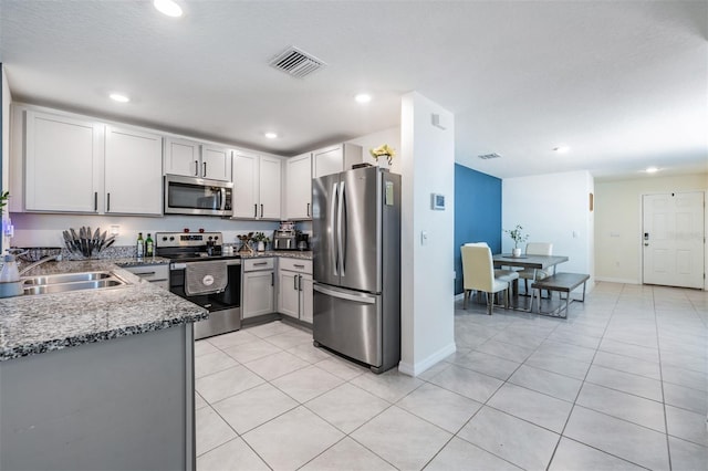 kitchen with stone counters, light tile patterned floors, a textured ceiling, and appliances with stainless steel finishes