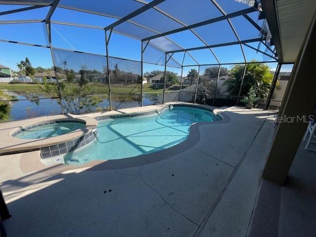 view of pool with an in ground hot tub, a water view, glass enclosure, and a patio area