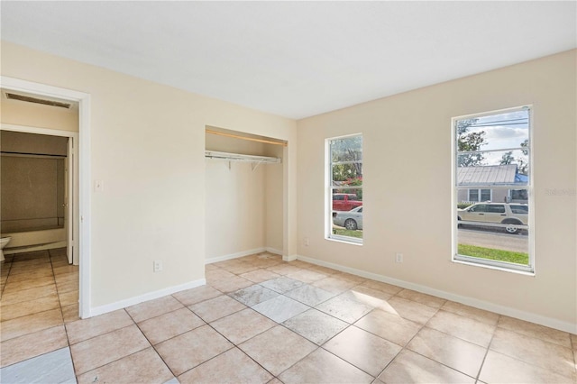 unfurnished bedroom featuring light tile patterned flooring, a closet, and multiple windows