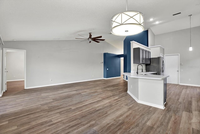 kitchen with kitchen peninsula, stainless steel fridge, dark hardwood / wood-style flooring, ceiling fan, and decorative light fixtures