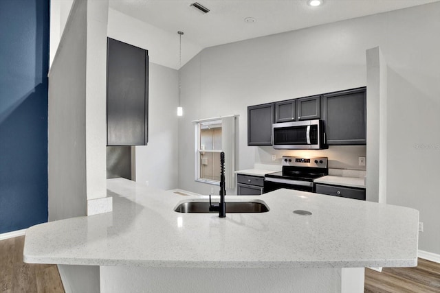 kitchen featuring light stone countertops, stainless steel appliances, sink, decorative light fixtures, and hardwood / wood-style flooring