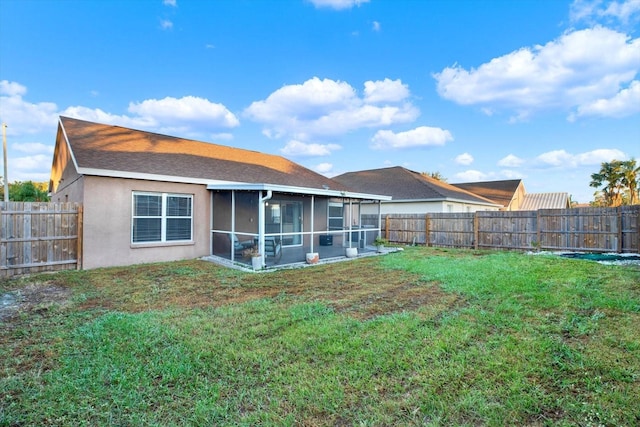 rear view of house featuring a sunroom and a lawn