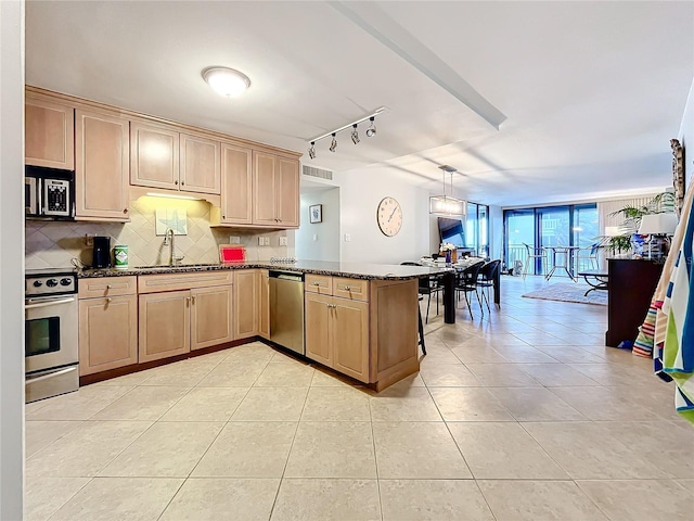 kitchen with pendant lighting, sink, light tile patterned floors, appliances with stainless steel finishes, and kitchen peninsula