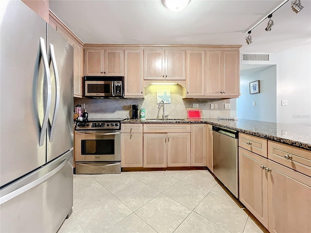 kitchen featuring tasteful backsplash, dark stone counters, stainless steel appliances, sink, and light tile patterned floors