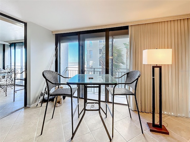 dining room featuring a healthy amount of sunlight, a wall of windows, and light tile patterned floors