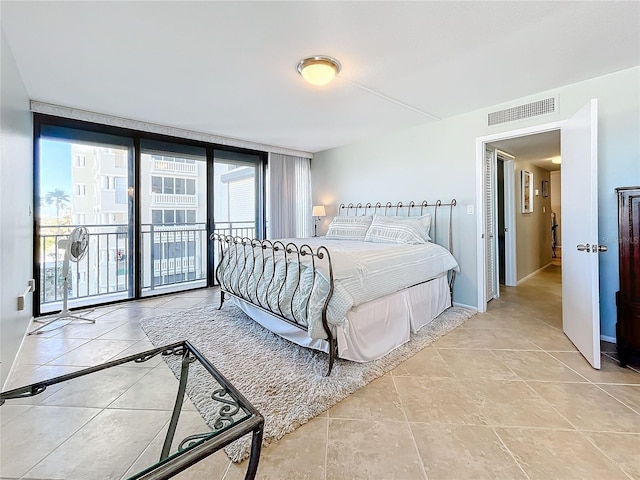 tiled bedroom with a wall of windows, access to outside, and multiple windows