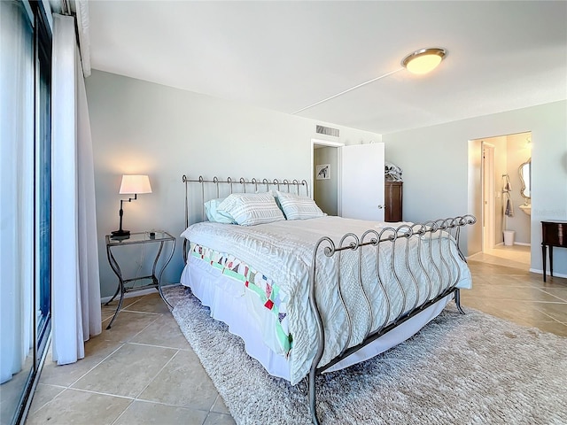 bedroom with ensuite bathroom and light tile patterned floors