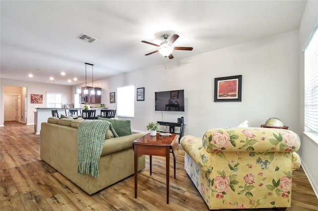 living room with plenty of natural light, hardwood / wood-style floors, and ceiling fan with notable chandelier