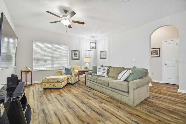 living room with ceiling fan with notable chandelier and light wood-type flooring