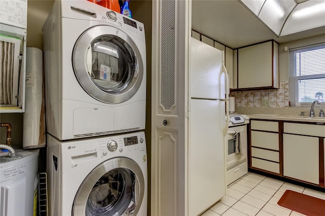 laundry area featuring light tile patterned flooring, sink, stacked washer and dryer, and water heater