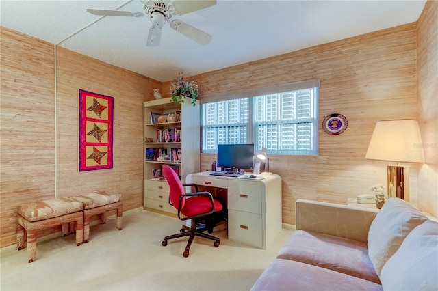 office featuring carpet flooring, ceiling fan, and wood walls