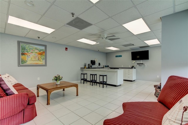 living room with a drop ceiling, ceiling fan, and light tile patterned flooring