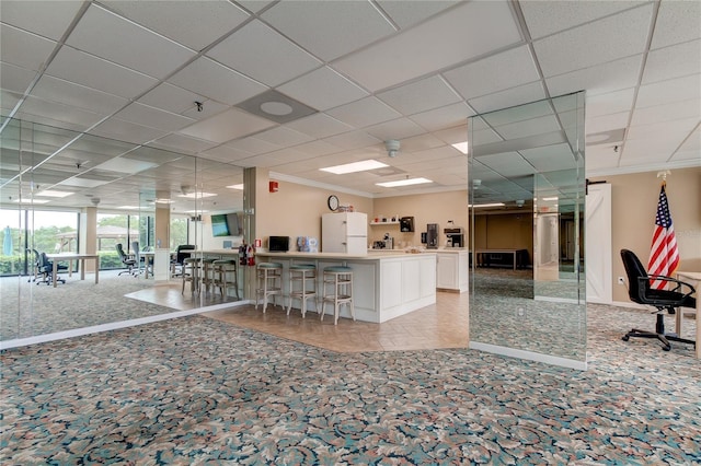 interior space with light carpet, white cabinets, a kitchen breakfast bar, ornamental molding, and white fridge