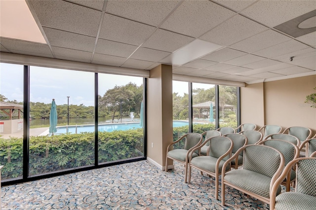 unfurnished sunroom with a drop ceiling and a water view