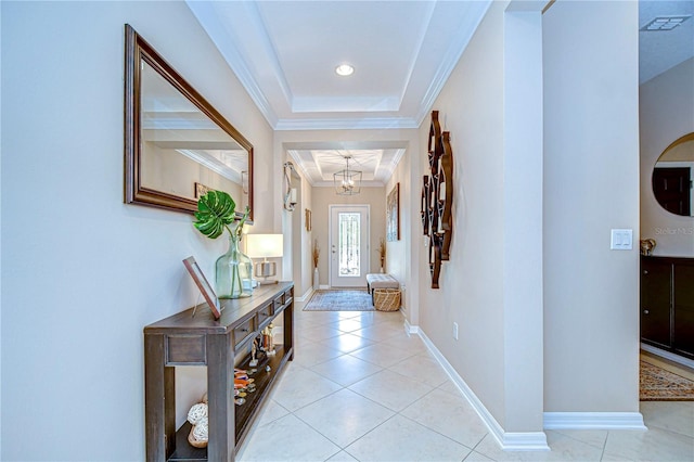 interior space with light tile patterned floors, a tray ceiling, an inviting chandelier, and ornamental molding