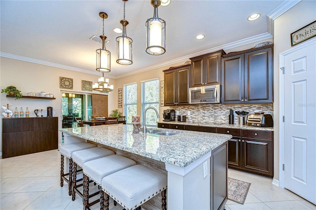 kitchen with a center island with sink, pendant lighting, dark brown cabinets, and sink