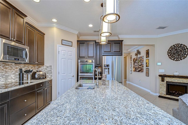 kitchen featuring dark brown cabinets, stainless steel appliances, and light stone counters