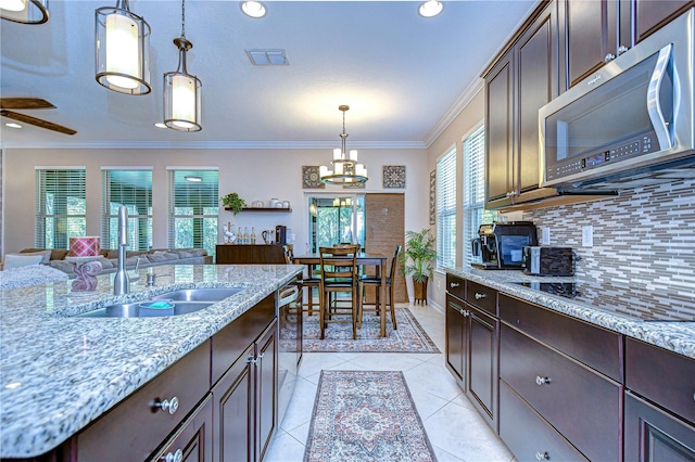 kitchen with appliances with stainless steel finishes, dark brown cabinetry, crown molding, sink, and pendant lighting