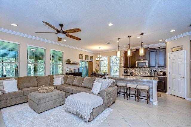 living room with a textured ceiling, light tile patterned flooring, ceiling fan with notable chandelier, and ornamental molding