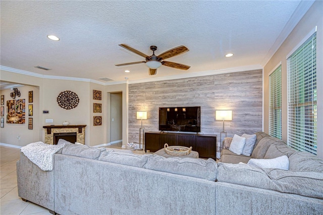 living room with crown molding, ceiling fan, light tile patterned floors, a textured ceiling, and a fireplace