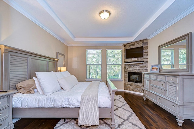 bedroom with a raised ceiling, dark hardwood / wood-style flooring, and multiple windows