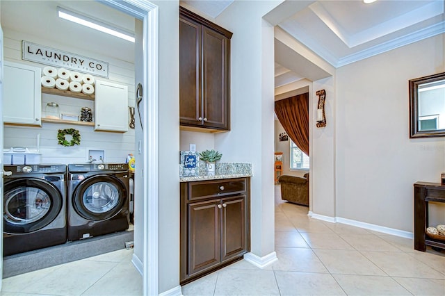 washroom featuring washer and clothes dryer, light tile patterned flooring, cabinets, and crown molding