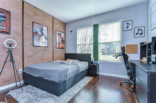 bedroom featuring a textured ceiling, dark hardwood / wood-style flooring, and brick wall