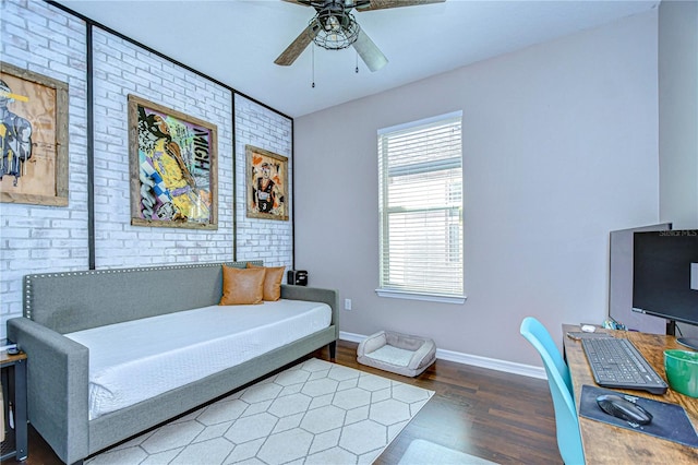 interior space with dark hardwood / wood-style floors, ceiling fan, and brick wall