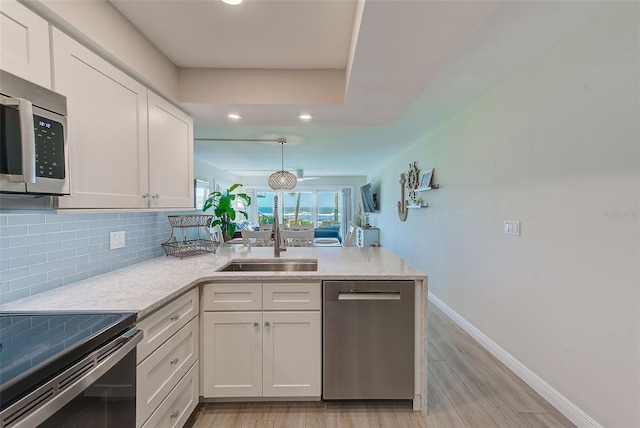 kitchen featuring tasteful backsplash, white cabinetry, stainless steel appliances, and a sink