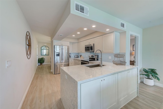 kitchen with appliances with stainless steel finishes, white cabinetry, visible vents, and light stone counters