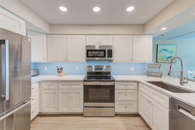 kitchen with appliances with stainless steel finishes, white cabinetry, and a sink