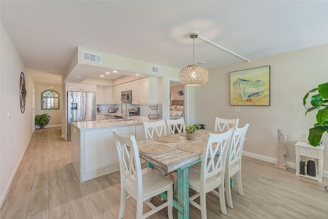 dining space featuring light wood finished floors, baseboards, visible vents, and recessed lighting